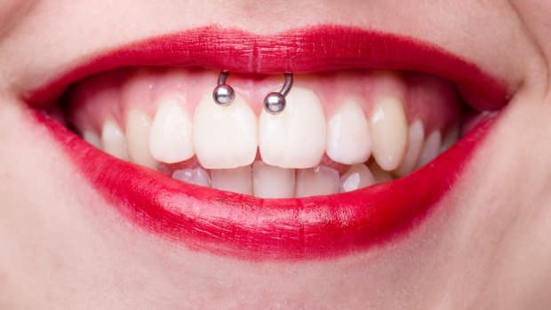 person with red lipstick and a smiley piercing.