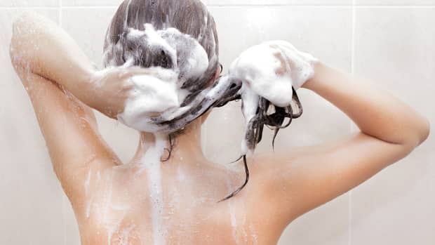 a woman shampooing her hair in the shower, from the back