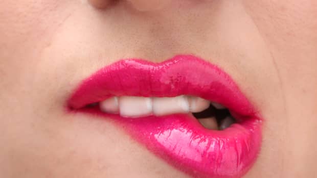 a woman with hot pink lips who's biting her bottom one