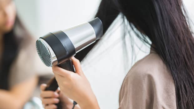 close up of a woman blow drying her hair