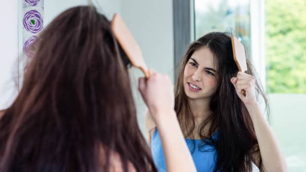 woman combing her hair in the mirror