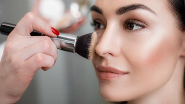 woman applying makeup to her cheeks.
