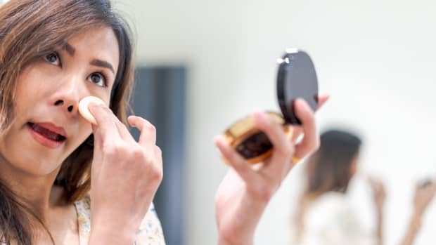 woman puts makeup onto her face.