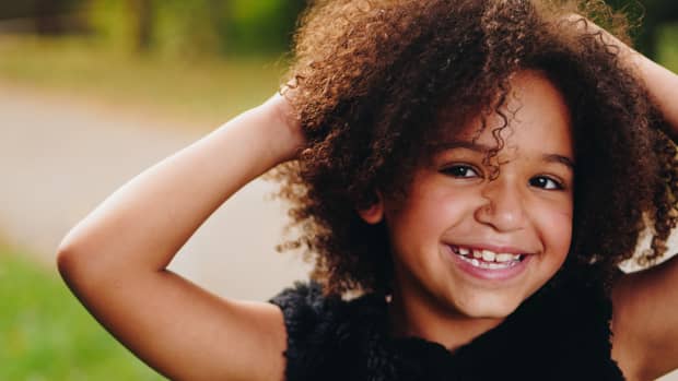 mixed child smiling and touching her hair.
