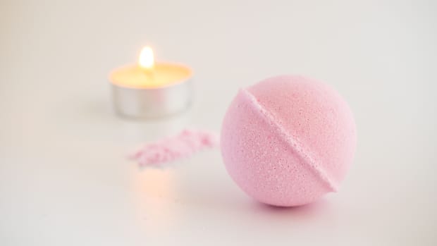 pink bath bomb with a tea candle in the background