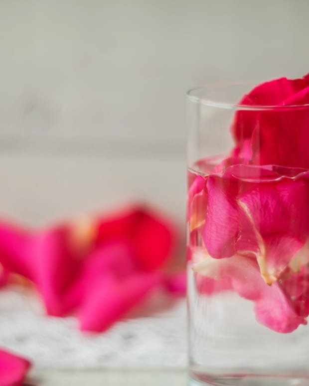 a glass of rosewater with rose petals